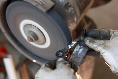 Atölyedeki metal işçisi öğütme aletini kullanıyor. Kıvılcım yaratan öğütücü ekipmanlara karşı el ele tutuşur. sanayi sürecine odaklanmış bakış