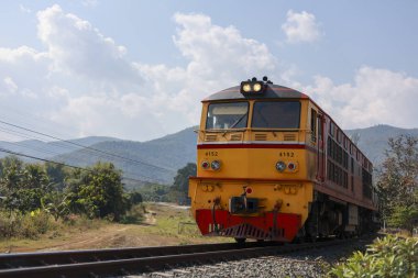 Sarı dizel lokomotif treni güzel dağ manzarası boyunca tren yolculuğunda. Bu ulaşım aracı kırsalda seyahat ediyor macera hissi yaratıyor.