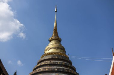 Tayland 'daki Budist tapınağında görkemli bir altın stupa. Bu dingin ruhani mimari berrak mavi gökyüzüne karşı dimdik ayakta duruyor. Huzurlu bir huzur hissi uyandırıyor.