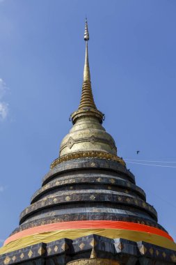 Tayland 'daki kutsal tapınakta görkemli antik altın stupa. Mavi gökyüzüne karşı ruhani Budist mimarisi, bir ibadet, inanç ve barışçıl gelenek simgesi.