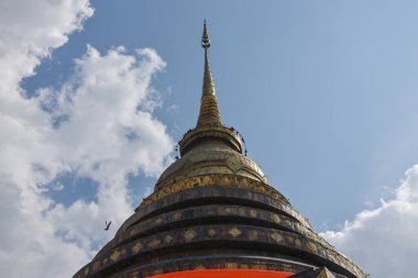 Mavi gökyüzünün altında beyaz bulutlu antik bir Budist tapınağında yüksek kuleli görkemli altın bir stupa. Kutsal ve dinsel mimarinin huzur dolu bir parçası.