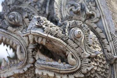 Antik ejderha, Asya 'daki tapınakta taş heykel heykelini detaylıca oyuyor. Mitoloji ve ruhani kültürden dokulu yüzeyi olan güçlü bir görüntü.