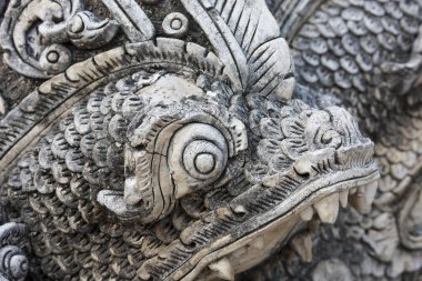 Acımasız, çok güçlü detaylarla oyulmuş eski taş ejderha. Asyalı mitolojik bir yaratığa yakından bakın pulları, dişleri ve karmaşık tapınak sanatını ve kültürünü gösteren bir heykel.