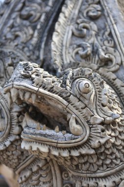 Vahşi antik Tayland Naga yılan heykeli oyması. Asya 'daki Budist tapınağından gelen karmaşık detaylarla taştan bir muhafız mitolojinin gücünü temsil ediyor.