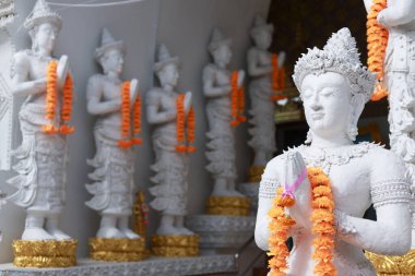 Tayland tanrısının heykeli turuncu bir çiçek çelengiyle süslenmiş. Antik dini, geleneksel Asya kültürünü ve tapınaktaki sanatı temsil eden barışçıl heykel