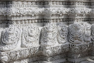Tayland tapınağının duvarında karmaşık beyaz sıva oyma ayrıntıları var. Süslü, antik bir mimari heykel deseni, Asya 'dan gelen muhteşem işçiliğe sahip ruhani tasarım.