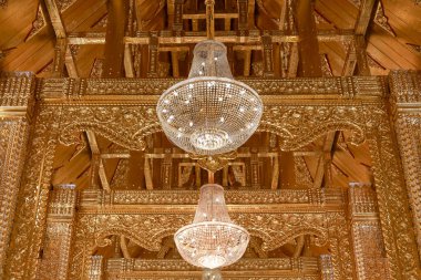 Altın ahşap oyma tavanlı görkemli iç mimari. Sakin kristal avize ışığı ve lamba asılı, varlıklı ve görkemli bir atmosfer yaratıyor.