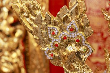 Süslü, altın bir heykelin, geleneksel Asya sanat eserinin detaylarını kapat. Güzel kırmızı ve beyaz mücevherlerle süslenmiş karmaşık ve kutsal mitolojik bir yaratık tasarımı.