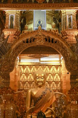 Kutsal tapınağın içindeki huzur dolu altın Buda heykeli. Asya kültürü ve dininin bu ruhani simgesi, süslü bir sanat eseri, sessiz meditasyona ve tapınmaya ilham veriyor.