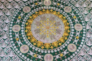 Süslü yeşil ve altın geometrik tavan deseni. Karmaşık bir ruhani tasarımı var. İslami kültürden simetrik arabesk dekorasyonu içeren soyut bir çember arkaplanı