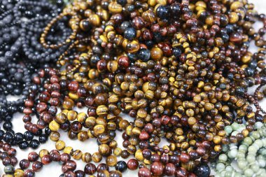 Renkli kaplan gözü taşından bilezik yığını. İyi şans ve ruhsal şifa için aksesuar. Pazarda satılık güzel değerli taşlar koleksiyonu.