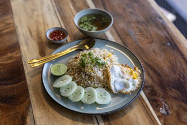 Lezzetli Tayland pilavı, kızarmış yumurta, taze salatalık, limon ve ahşap masada çorba ile servis edilir. çok iştah açıcı ve rahatlatıcı Asya mutfağı öğle yemeği
