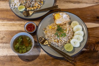 Khao Pad 'in kızarmış pirinçli ve ahşap masadaki Pad Thai şehriyeli leziz Tayland yemeğinin iştah açıcı görüntüsü, öğle yemeği için mükemmel.