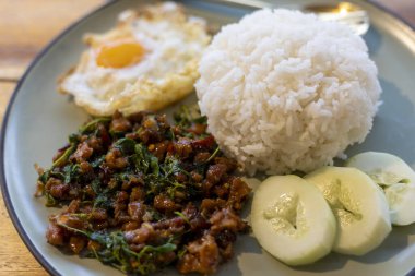 Lezzetli pad kra pao, baharatlı Tayland fesleğeni pilav ve sahanda yumurta. Tabaktaki popüler Tayland yemeği Asya mutfağını temsil ediyor. Gerçekten doyurucu ve iştah açıcı.