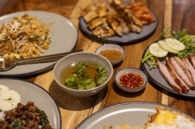 Tahta masada Tayland yemeği ziyafeti ızgara domuz eti, baharatlı sos, erişte ve pilavla iştah açıcı bir akşam yemeği. Lezzetli Asya yemekleri paylaşmak için harika.