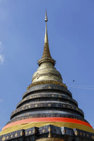 Tayland 'daki kutsal tapınakta görkemli antik altın stupa. Mavi gökyüzüne karşı ruhani Budist mimarisi, bir ibadet, inanç ve barışçıl gelenek simgesi.