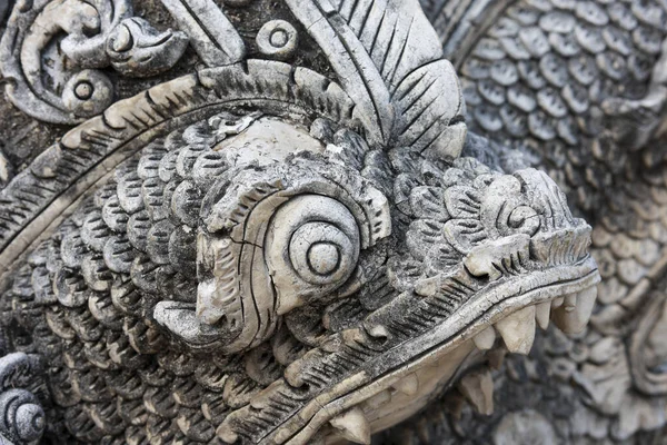 Acımasız, çok güçlü detaylarla oyulmuş eski taş ejderha. Asyalı mitolojik bir yaratığa yakından bakın pulları, dişleri ve karmaşık tapınak sanatını ve kültürünü gösteren bir heykel.