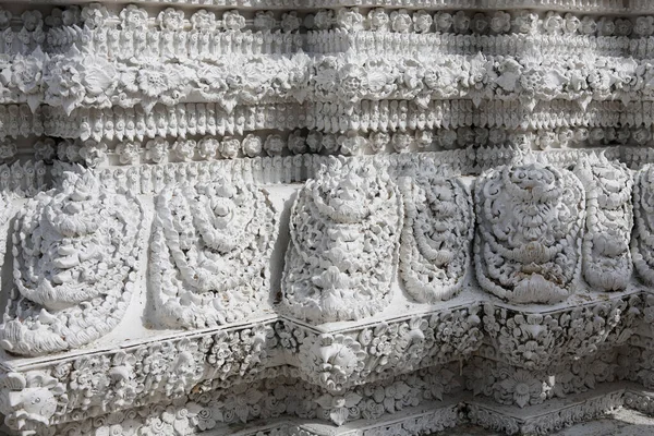 Tayland tapınağının duvarında karmaşık beyaz sıva oyma ayrıntıları var. Süslü, antik bir mimari heykel deseni, Asya 'dan gelen muhteşem işçiliğe sahip ruhani tasarım.