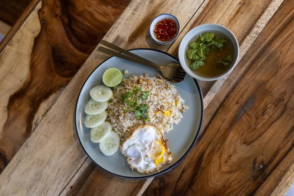 Lezzetli Tayland yemekleri, Khao Pad kızarmış pirinci, otantik Asya mutfağı yemeği. Öğle yemeği için popüler yemek ya da tabakta kızarmış yumurta, çorba ve ahşap masada kırmızı biber.