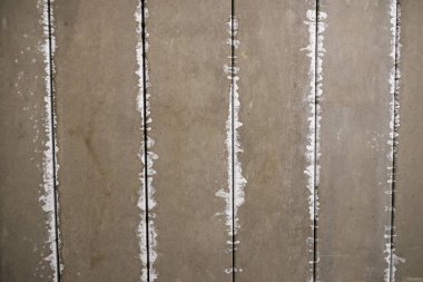 Eski gri beton duvar, pürüzlü yüzey dokusu ve beyaz dikey çizgi birleşik dolgu, yıpranmış ve endüstriyel yapı kalıplarını kirli detay arka plan kağıdıyla gösteriyor.