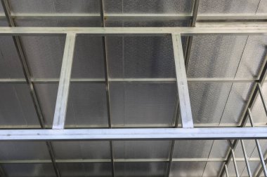 Gümüş yalıtım örtüsü olan dayanıklı metal çatı yapısının düşük açılı görüntüsü, sağlam kiriş çerçeveli ısı endüstriyel inşaat alanından korunma ve korunma sağlıyor.