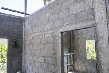 Kalkınma sürecini ve endüstriyel yapısal konut çalışmalarını temsil eden inşaat tamamlanmamış beton duvar ve metal kapı çerçevesini gösteren inşaat alanı.