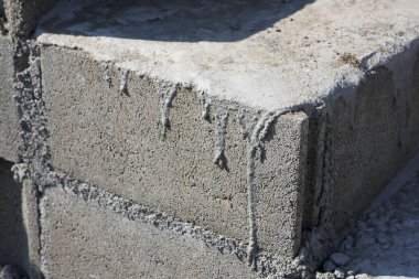 Sert beton merdiven bloğunun köşesi dağınık gri havan damlası dokusu sağlam endüstriyel yapı malzemesi soyut desen ve işlenmemiş çimento yüzeyi gösteriyor.