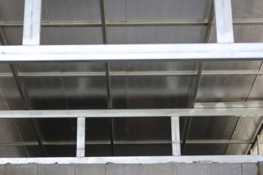 Düşük açı görünümü, dayanıklı metal çatı yapı iskeletini basit endüstriyel tasarımı ve doğrusal geometrik desen içeren şeffaf tavan panelini desteklerken gösterir