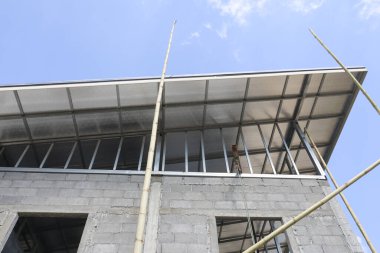 Beton blok duvar ve metal çatı yapısına sahip, mavi gökyüzü arka planına karşı alçak açılı modern bina inşaatına bakın, sağlam yerleşim sanayiinin umut verici ilerlemesini aktarıyor