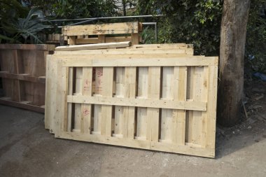 Yığılmış çiğ kereste paletleri ve ahşap sandık yapıları nakliye için hazır bekliyor. Açık hava deposunda sağlam çam ve endüstriyel dokular kargo bekliyor.