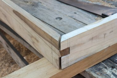 Tamamlanmamış ahşap işçiliği, eklem köşesi bağlantısını, kalem izleri ve el testeresi ile kaba ahşap çerçeve inşaatını, titiz işçiliği ve hassasiyetini göstermektedir.