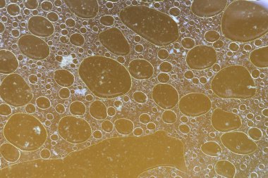 Çorba sıvı yüzeyinde yüzen yağlı sarı yağ baloncuğunun soyut dokusunu kapat ve ilginç bir yağ çemberi yapısı oluştur.