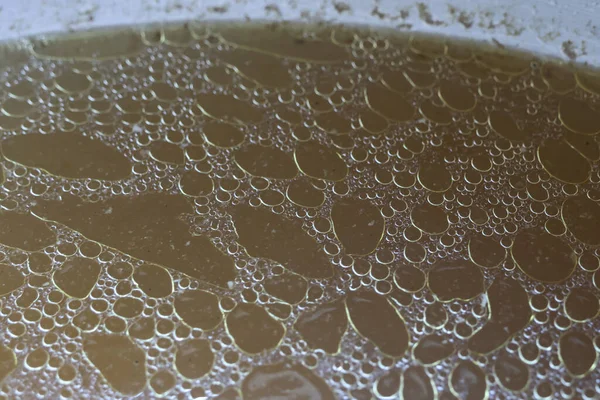 Yakından bakınca yağlı tavuk çorbası ya da yağ köpükleriyle dolu et suyu yüzeyi zengin dokuları ve leziz ev yapımı pişirme stokları için lezzetli altın sıvıları gösteriyor.