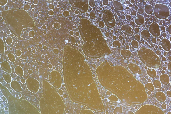 Soyut kahverengi yağ ve su karışımı dokusu benzersiz yuvarlak baloncuk şekilleri gösteriyor. Sıvı yüzeyde hareketsiz sanatsal duygularla yüzen şekiller.