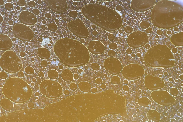 Çorba sıvı yüzeyinde yüzen yağlı sarı yağ baloncuğunun soyut dokusunu kapat ve ilginç bir yağ çemberi yapısı oluştur.