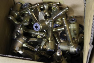 Endüstriyel pirinç kapakçık ve uygun parçalarla dolu bir kutunun içinde dağınık bir şekilde. Tesisattan ya da makineden gelen bu altın metal hurda tasnif ya da geri dönüşüm bekliyor.