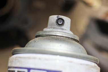 Kirli, kullanılmış sprey spreyin kapağını kapat. Endüstriyel arka plan bulanık, kapakçık ve etkinleştirici üzerinde pratik, odaklanmış duygu ile vurgulama ayrıntıları