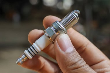 Odaklanmış mekanik el yeni buji tutuyor. Otomotiv tamiri ve araç bakımı için önemli bir motor parçası, garajdaki ateşleme sistemi servisi için çok önemli.
