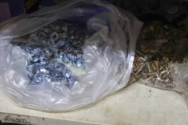 Fındık ve cıvata çeşnili büyük bir sanayi metal donanım çantası. Bağlayıcılar dağınık atölye ortamında inşaat ve onarım çalışmaları için hazırlar.