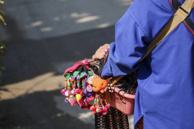 Yerel pazarda satmak için bir sepet renkli el işi ve hediyelik eşya satan bir sokak satıcısı. Günlük geçim ve geleneksel kültürün basit tasviri
