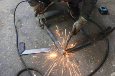 İnşaat için koruyucu eldiven kaynak metaliyle odaklanmış endüstriyel işçiler. Fabrikadaki imalat işi profesyonel ekipmanlarla parlak kıvılcımlar yaratıyor.