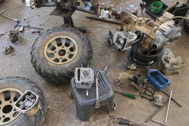 Dağınık garaj zemini parçalanmış motor, parça, tekerlek ve alet gösteriyor. sahne kaotik atölyedeki karmaşık araç onarım ve bakım projesini yansıtıyor