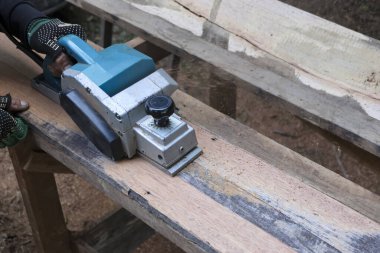 Marangozluk işine odaklanmış, ahşap işçiliği için elektrikli bir planör kullanıyor. Bu marangozluk ustalığı, inşaat veya yenileme projesi için pürüzsüz ahşap kalas içeriyor.