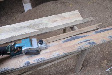 Odaklanmış bir zanaatkar ahşap bir aletle çalışıyor. Bu marangozluk yenileme ve DIY projesi yeni bir son için eski yüzeyin pürüzsüzleştirilmesini içeriyor