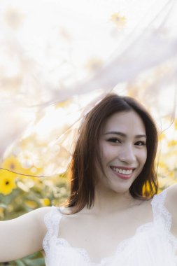 Beyaz elbiseli mutlu kadın dışarıda güzel bir yaz gününün tadını çıkarıyor. Saf neşe ve güzelliğin portresi Parlak sarı ayçiçeği tarlasında