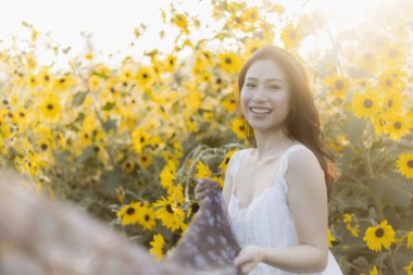 Dışarıdaki sarı çiçek tarlasında gülümseyen güzel mutlu kadın. Güzel doğanın ve ılık altın güneş ışığının tadını çıkaran genç bir insan portresi.