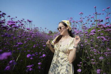 Mor çiçek tarlasında duran mutlu güzel kadın. Neşeli genç insan yaz tatilinin tadını çıkarıyor. Güzel mor doğayla çevrili huzurlu bir an.
