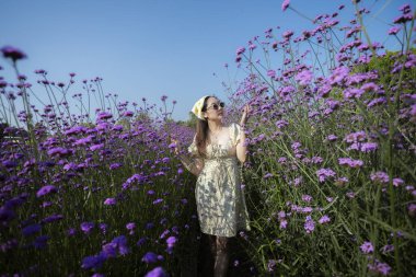 Uzun mor çiçek tarlasında duran altın elbiseli mutlu güzel kadın. Kaygısız insan kırsalda güzel bir günde doğanın ve yaz güneşinin tadını çıkarıyor.