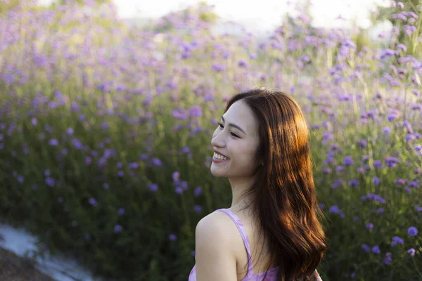 Mor çiçek tarlasında mutlu bir şekilde gülümseyen uzun saçlı güzel Asyalı kadın. Doğanın ve yazın tadını çıkaran, dingin hisseden bir kadının neşeli portresi.