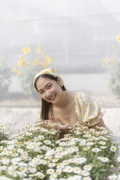 Güzel mutlu Asyalı kadın, portrede güzel bir gülümseme. Çiçek bahçesinde doğanın tadını çıkaran genç insan hoş bir bahar günü beyaz papatya çiçekleriyle dolu.